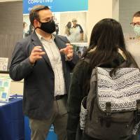 Two faculty discuss with a student while she listens intently